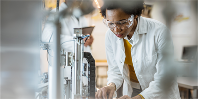 Photograph of a clinical lab personnel working alongside full lab automation to efficiently and productively process patient samples.