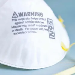 Photo of a white N95 mask with the word "warning" written on it.