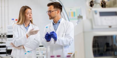 Photograph of two clinical lab personnel discussing how to best optimize liquid handling variables to ensure the success of their clinical assays.