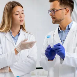 Photograph of two clinical lab personnel discussing how to best optimize liquid handling variables to ensure the success of their clinical assays.