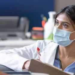 A female doctor bend's down to eye level as she talks with a cancer patient
