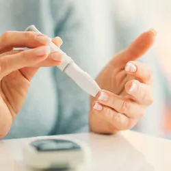 Mature woman doing blood sugar test at home in a living room