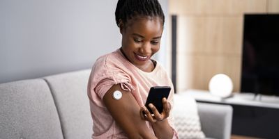 Woman Testing Glucose Level With Continuous Glucose Monitor On Mobile Phone