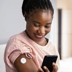 Woman Testing Glucose Level With Continuous Glucose Monitor On Mobile Phone
