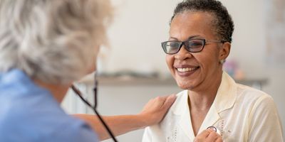 A senior black women is having her heart checked by a female doctor