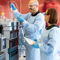 Photograph of clinical lab personnel working with a tandem quadrupole mass spectrometer.