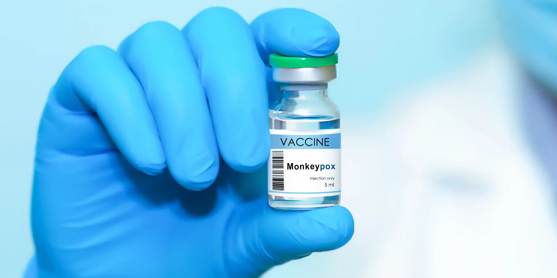 Doctor's hand in a medical glove holds a bottle with Vaccine Monkeypox