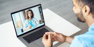 View over male client shoulder sit at desk receive medical consultation online from female doctor
