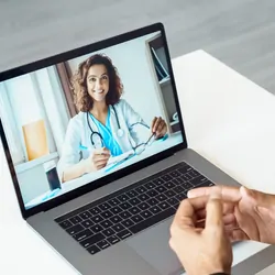View over male client shoulder sit at desk receive medical consultation online from female doctor
