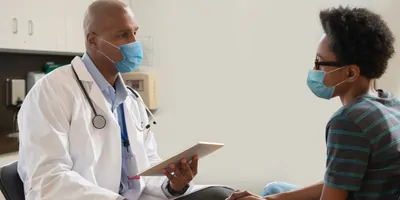 Doctor at hospital wearing mask taking care of young patient