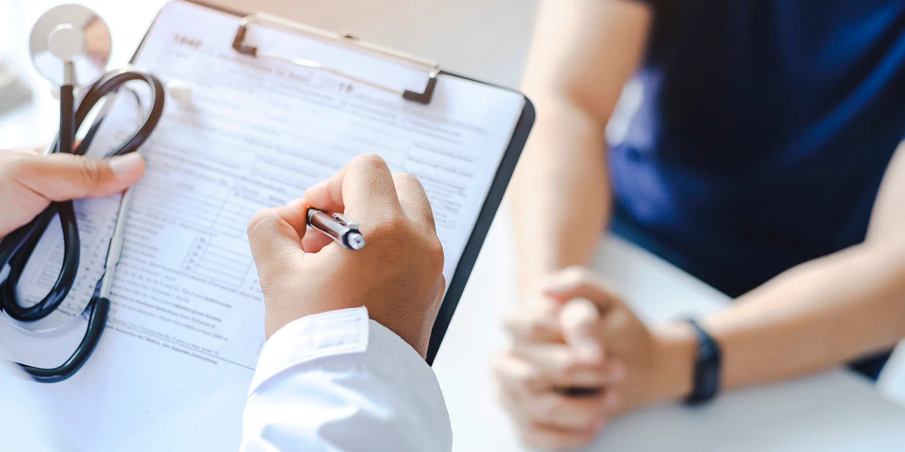 Close-up of a male doctor hand hold a silver pen and showing pad in hospital