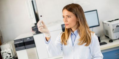Photograph of a clinical lab personnel holding up a sample for a LC-MS/MS assay.