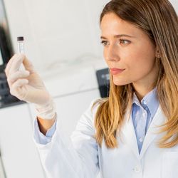 Photograph of a clinical lab personnel holding up a sample for a LC-MS/MS assay.