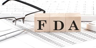 FDA written on wooden cubes next to charts and glasses