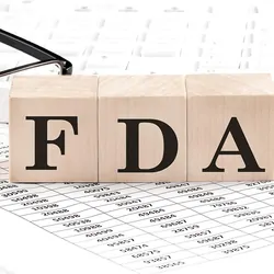 FDA written on wooden cubes next to charts and glasses