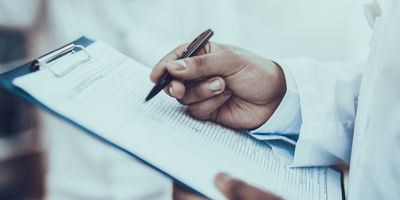 Photo of a Black clinical laboratory scientist holding a clipboard with a checklist for a lab inspection.