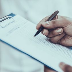 Photo of a Black clinical laboratory scientist holding a clipboard with a checklist for a lab inspection.