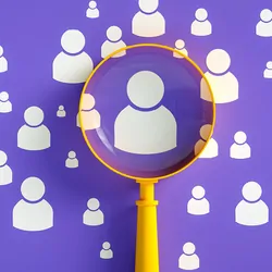 A representation of recruitment and retention showing a magnifying glass focusing on the person who is the right fit among others who may not be the best fit for a given team.