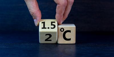 Male hand turns a cube to change "2 degrees Celsius" to "1.5 degrees Celsius."