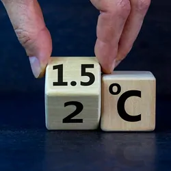 Male hand turns a cube to change "2 degrees Celsius" to "1.5 degrees Celsius."