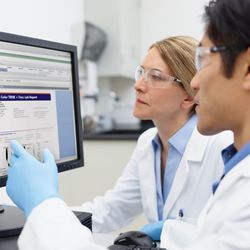 Photograph of lab personnel looking at clinical flow cytometry results on the FACSLyric software, displayed on monitors in front of them in the clinical lab.