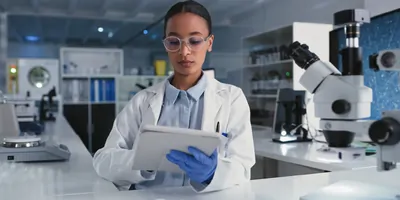 Photo of a Black clinical laboratory professional holding a clinical trial lab manual in a laboratory.