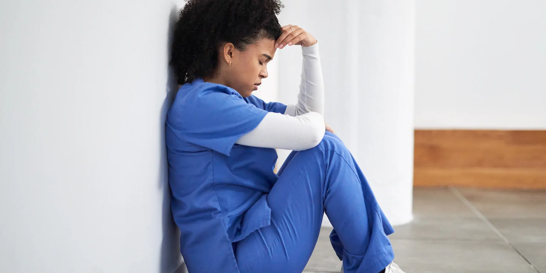 Health care worker looking stressed, sitting on the floor