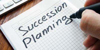 Photo of a clinical lab professional writing the words "succession planning" on a piece of paper.
