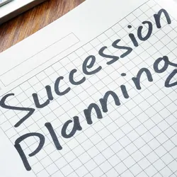 Photo of a clinical lab professional writing the words "succession planning" on a piece of paper.