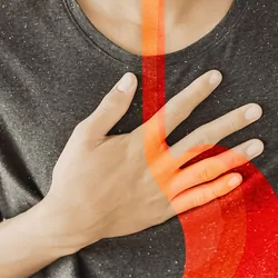 Person experiencing stomach distress with an overlay of the gastroesophageal junction in red
