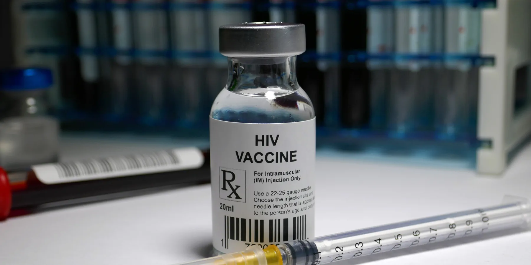 A bottle of medication listed as "HIV Vaccine" on a table