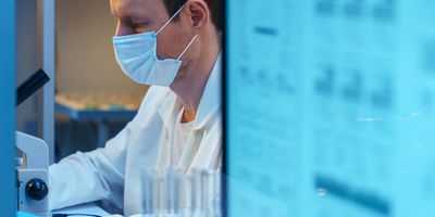 Scientist analyzing microscope and data