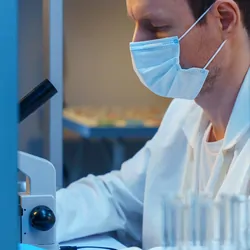 Scientist analyzing microscope and data