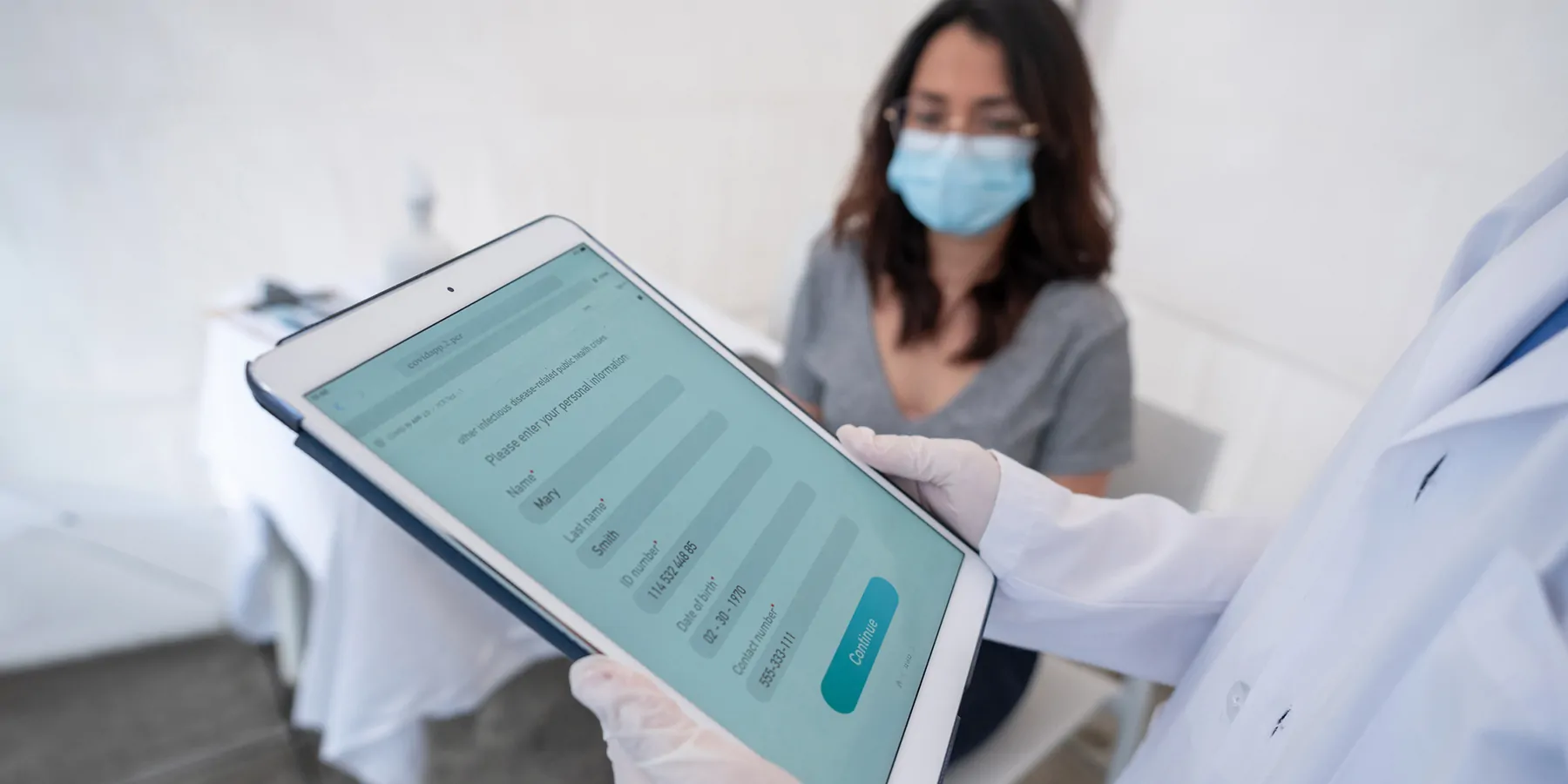 Clinical lab professional entering a woman’s electronic medical record at a clinic.