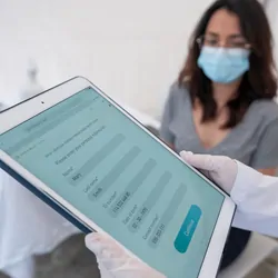 Clinical lab professional entering a woman’s electronic medical record at a clinic.
