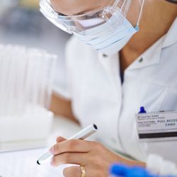 A young researcher recording her findings on a tablet in the lab