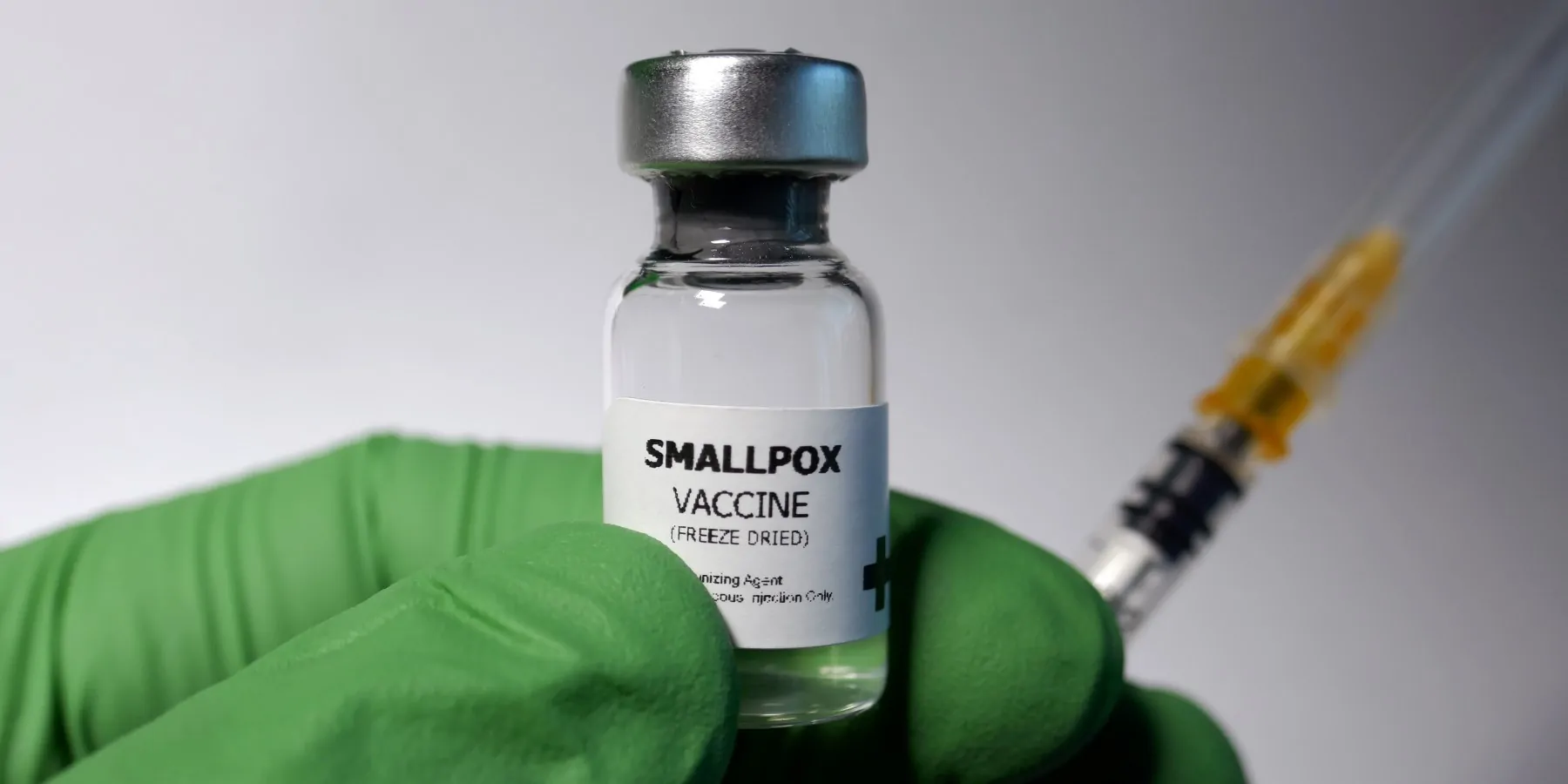 Gloved hand holding a bottle of smallpox vaccine