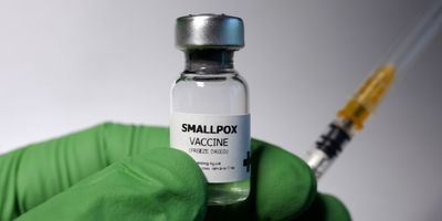 Gloved hand holding a bottle of smallpox vaccine
