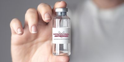 Photograph of a vial labelled monoclonal antibody held in someone’s palms, represent lecanemab administration. 