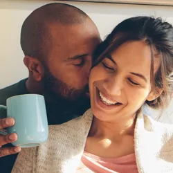 Couple cuddling in the morning with coffee