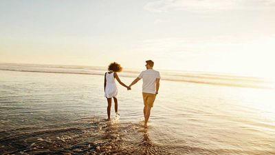 Couple holding hands walking in the water