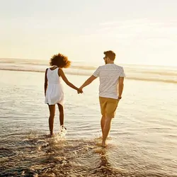 Couple holding hands walking in the water