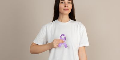 Woman in white shirt holding purple ribbon in her hand