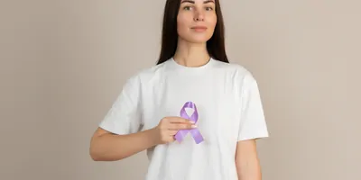 Woman in white shirt holding purple ribbon in her hand