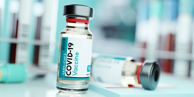 Two bottles of COVID-19 vaccine on a table, one is tipped on its side