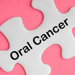 White puzzle piece with the words "Oral Cancer" written on it on a pink background