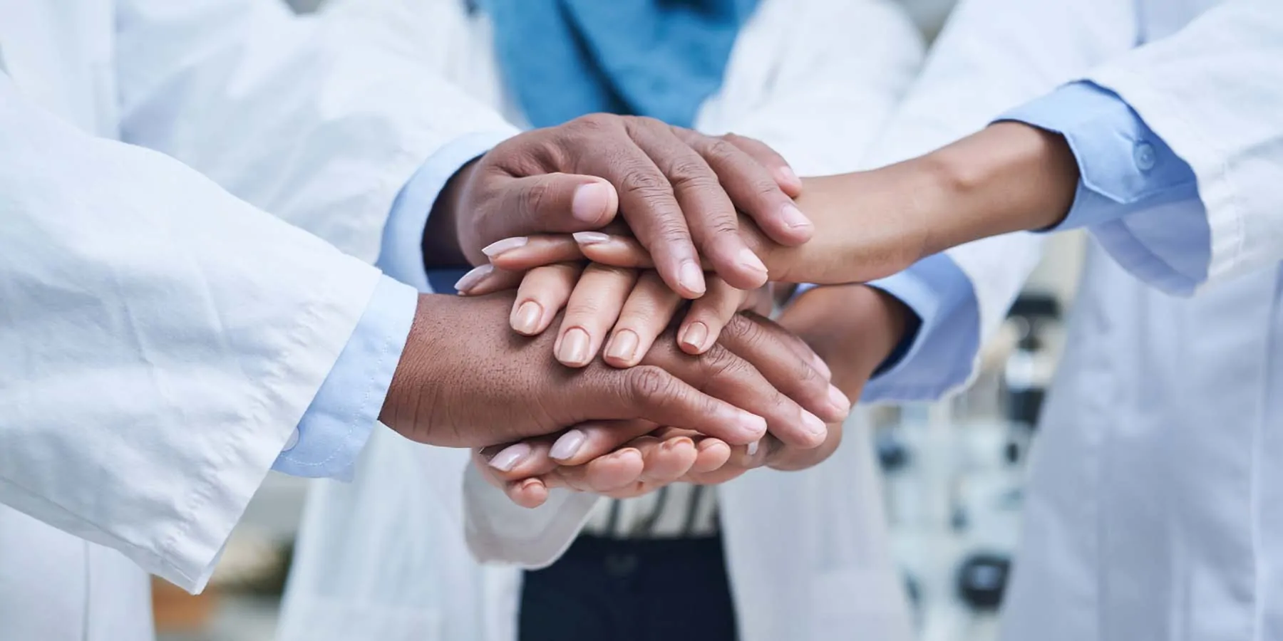 Doctors and lab technician team ptting their hands together