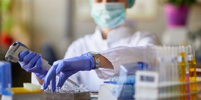 Photo of a clinical lab professional in the lab holding a pipette while developing a cell therapy.