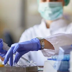 Photo of a clinical lab professional in the lab holding a pipette while developing a cell therapy.