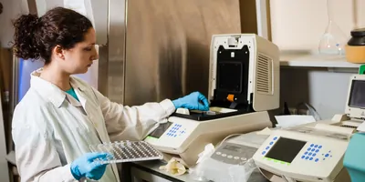 Researcher performing a step in multiplex testing, specifically placing PCR tubes in the thermocycler.